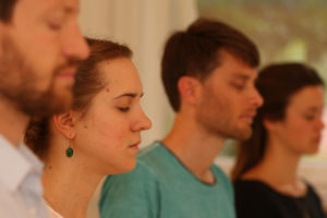 Eine Gruppe junger Meditierender mit geschlossenen Augen.