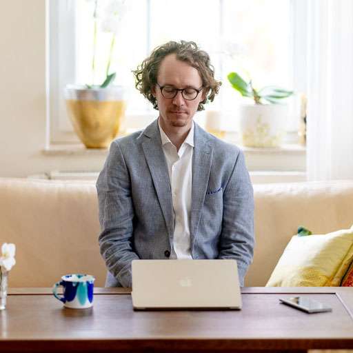 online-meditation-laptop-viktor Ein junger Mann sitzt mit geschlossenen Augen vor seinem Laptop und meditiert